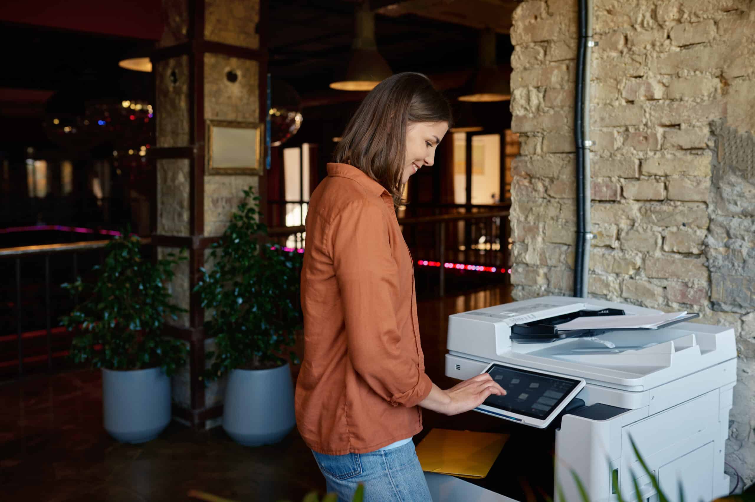 Professional woman using modern multifunction printer in stylish Saskatchewan office environment showing lease and rental equipment options